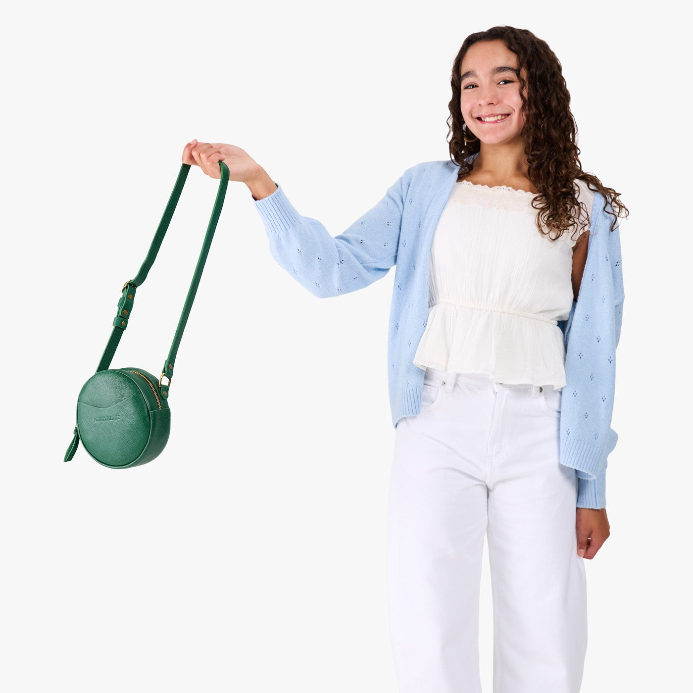 Bacalar | Model wearing a circle shaped crossbody bag with top zipper and gold accents