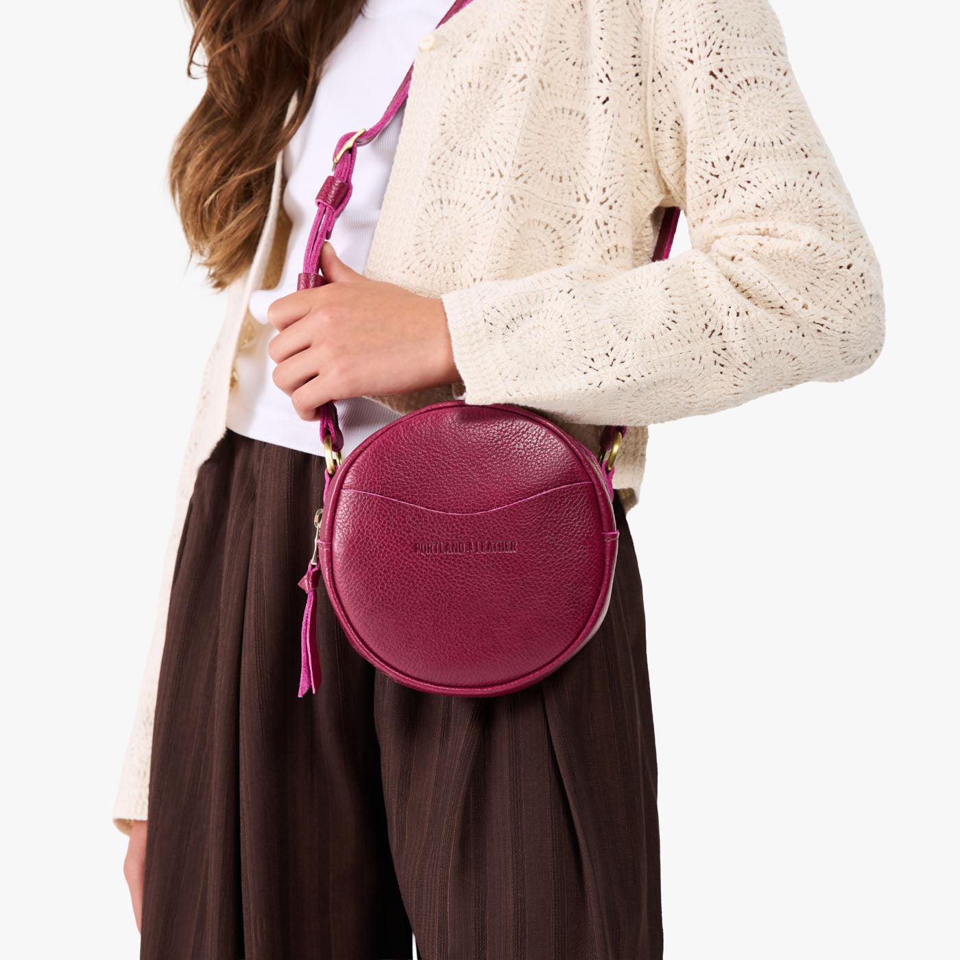 Orchid | Model wearing a circle shaped crossbody bag with top zipper and gold accents