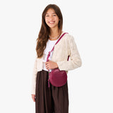 Orchid | Model wearing a circle shaped crossbody bag with top zipper and gold accents