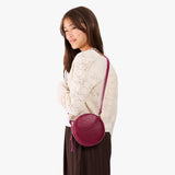 Orchid | Model wearing a circle shaped crossbody bag with top zipper and gold accents