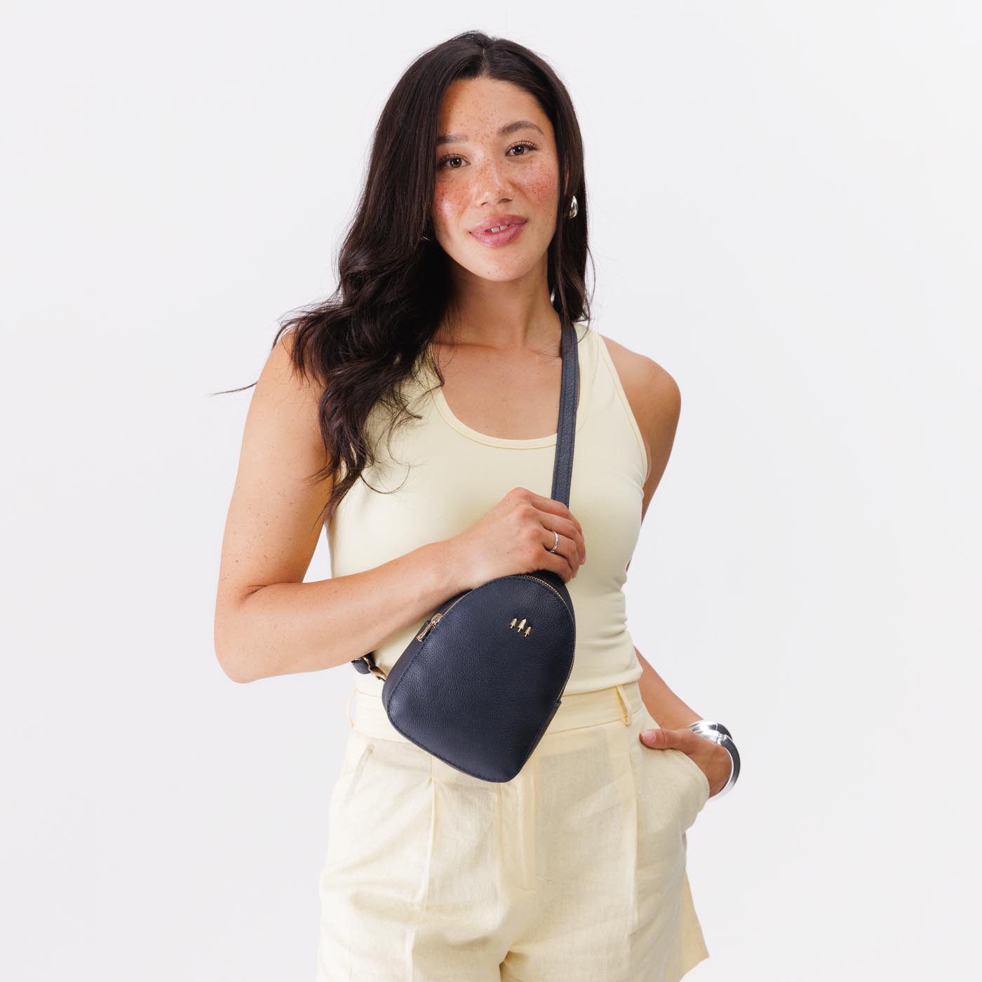 Night Owl | Model wearing small sling bag with zipper closure and adjustable strap