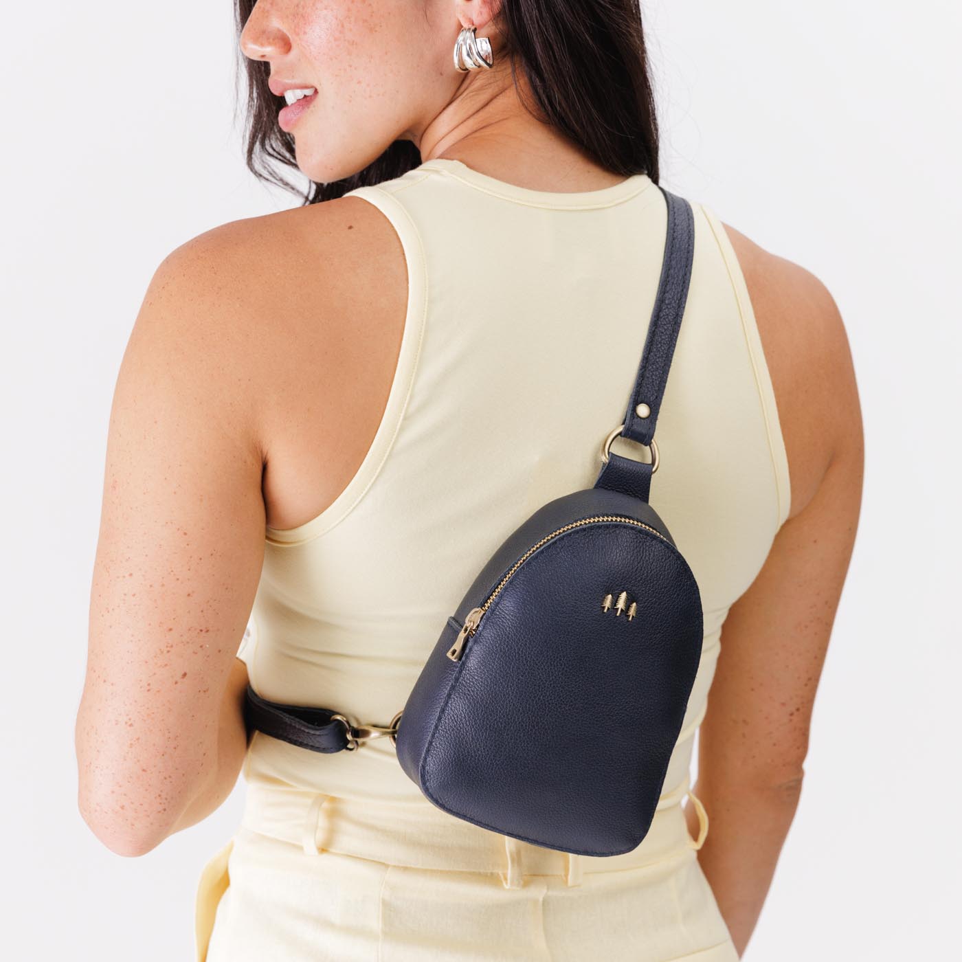 Night Owl | Model wearing small sling bag with zipper closure and adjustable strap