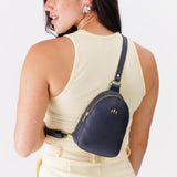 Night Owl | Model wearing small sling bag with zipper closure and adjustable strap