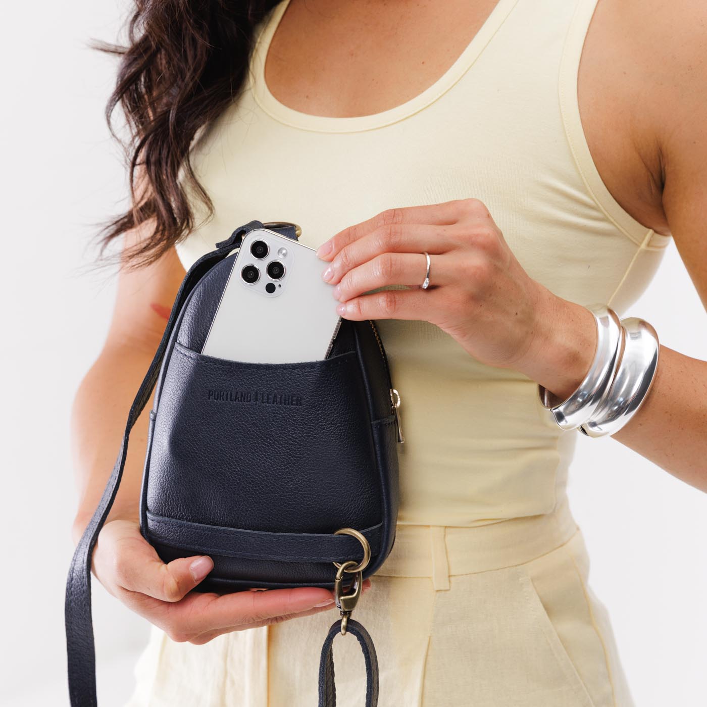 Night Owl | Model wearing small sling bag with zipper closure and adjustable strap