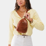 Nutmeg | Model wearing small sling bag with zipper closure and adjustable strap