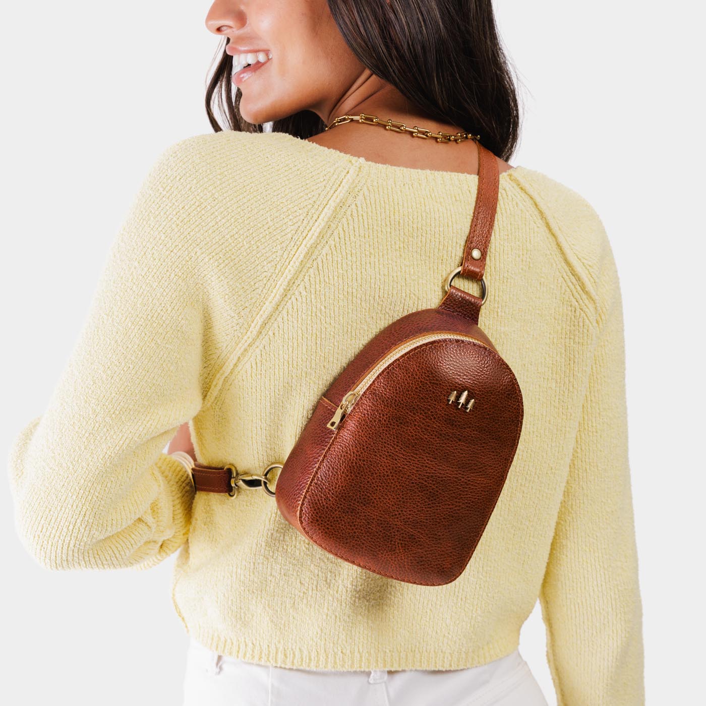 Nutmeg | Model wearing small sling bag with zipper closure and adjustable strap