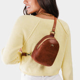 Nutmeg | Model wearing small sling bag with zipper closure and adjustable strap