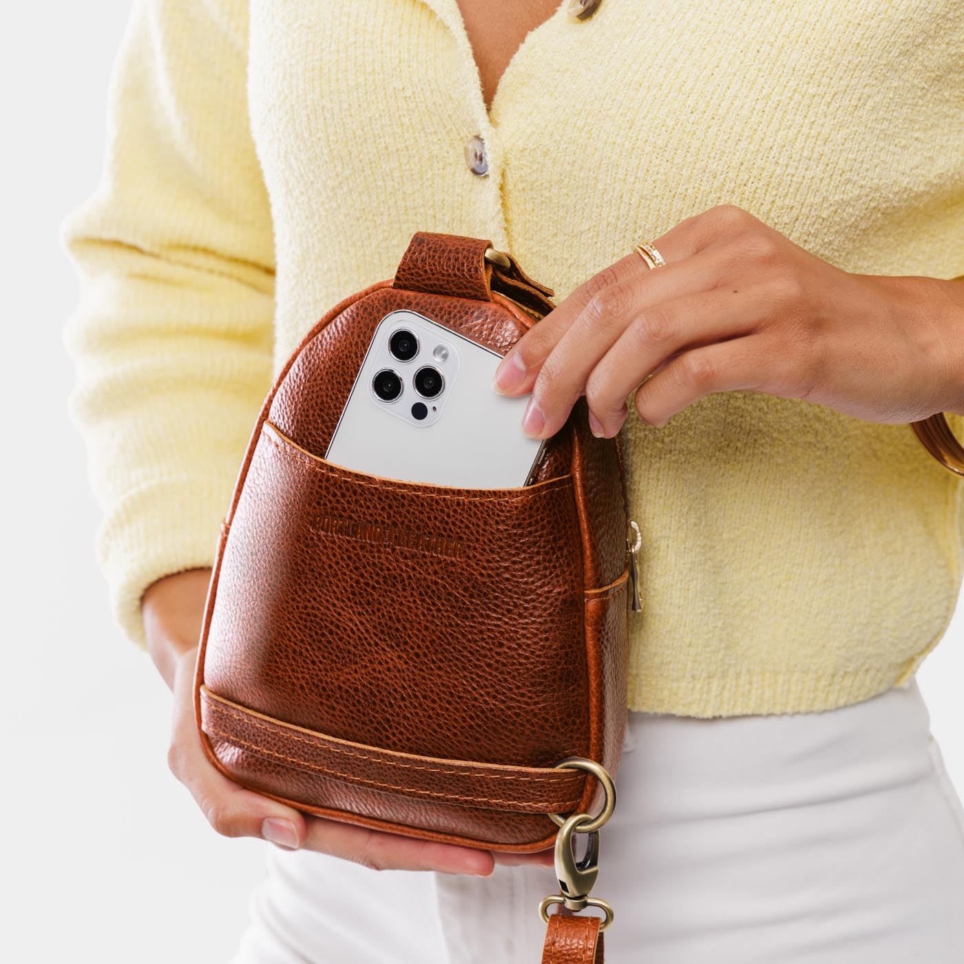 Nutmeg | Model wearing small sling bag with zipper closure and adjustable strap