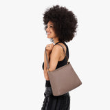 Sparrow Small | Model holding a triangular shoulder bag with antiqued brass finished 