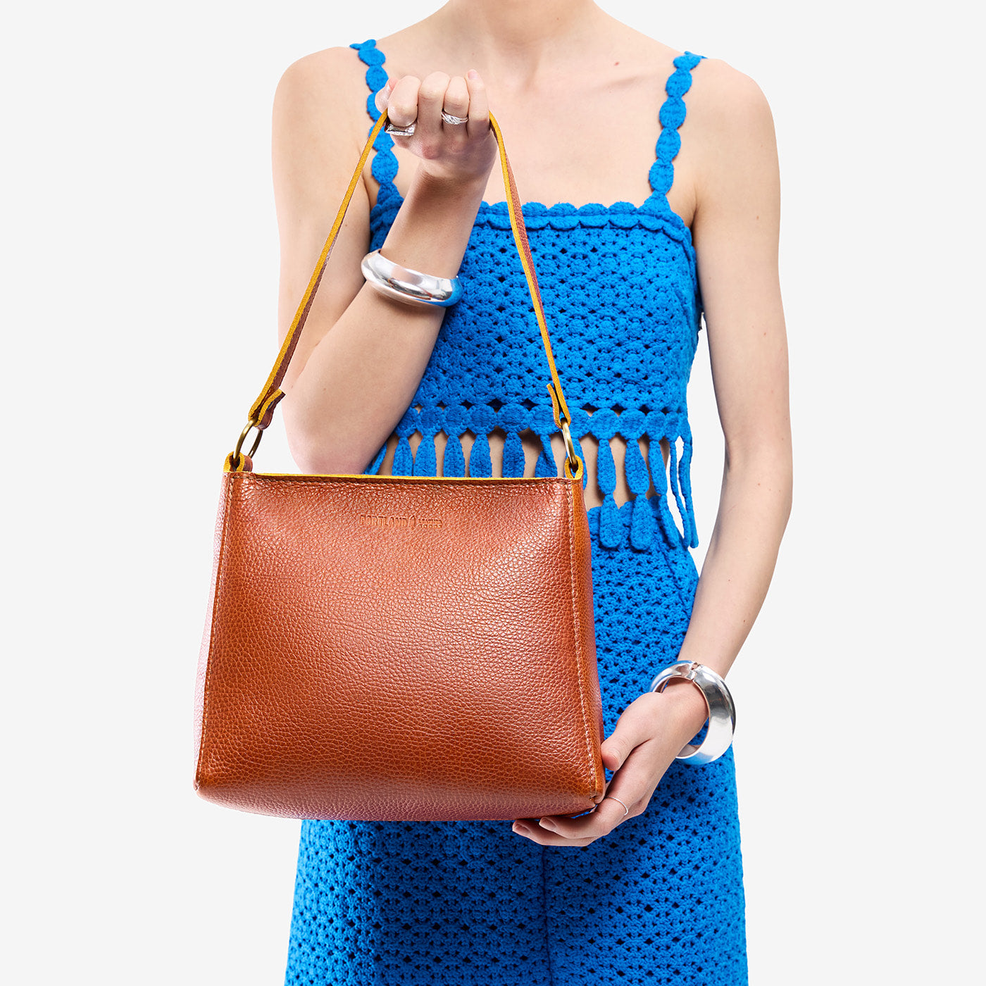 Sienna*Classic | Model holding triangular shoulder bag with antiqued brass finished hardware