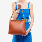 Sienna Classic | Model holding triangular shoulder bag with antiqued brass finished hardware
