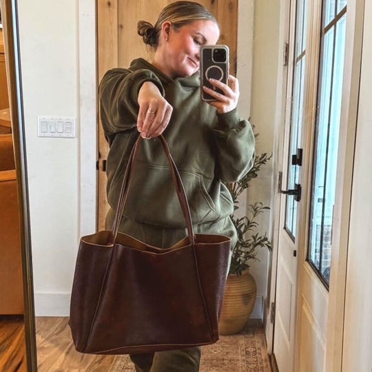 Person taking a mirror selfie holding a Coldbrew August Tote indoors.