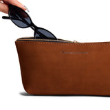 Wildwood | Model hand pulling pair of sunglasses from leather utility bag pouch with top zipper