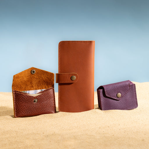 Three leather wallets arranged on sand against a blue gradient background featured image