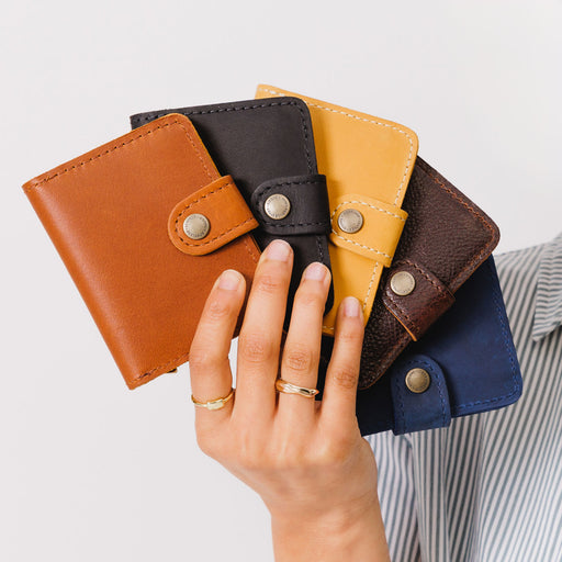 All Variants | Hand holding five different colored wallets with snap closures