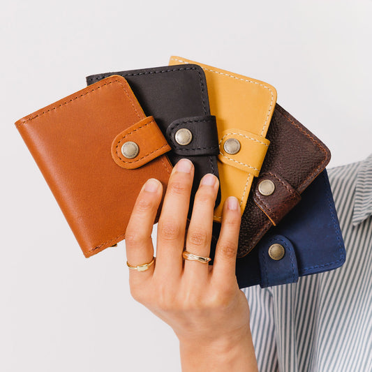 All Variants | Hand holding five different colored wallets with snap closures