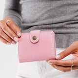 Vintage Pink | Model holding small leather bifold wallet with snap closed