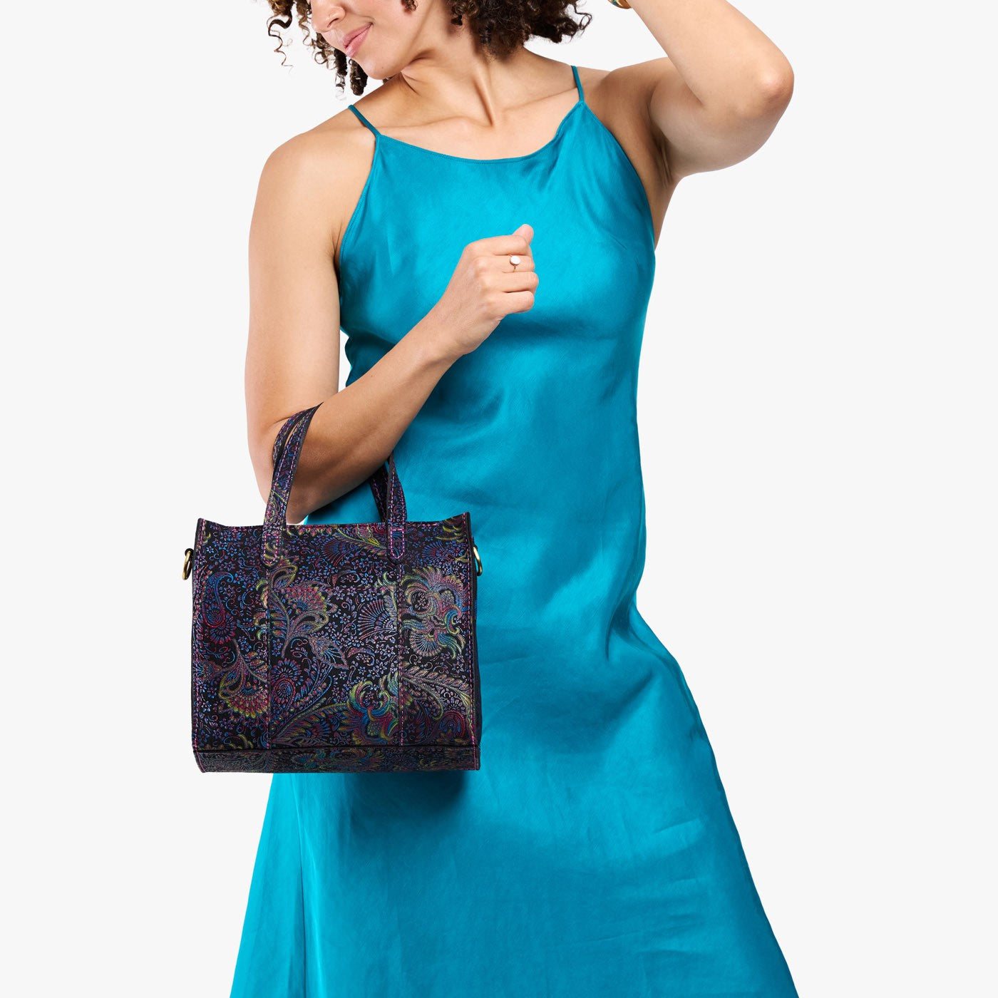 Carnival | Model holding structured mid-size tote bag with overlapping panels and crossbody strap