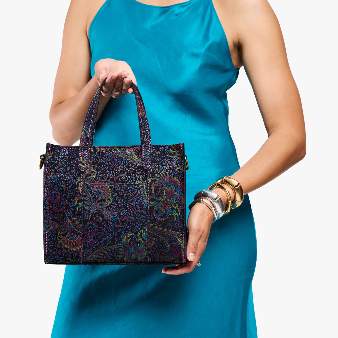 Carnival | Model holding structured mid-size tote bag with overlapping panels and crossbody strap