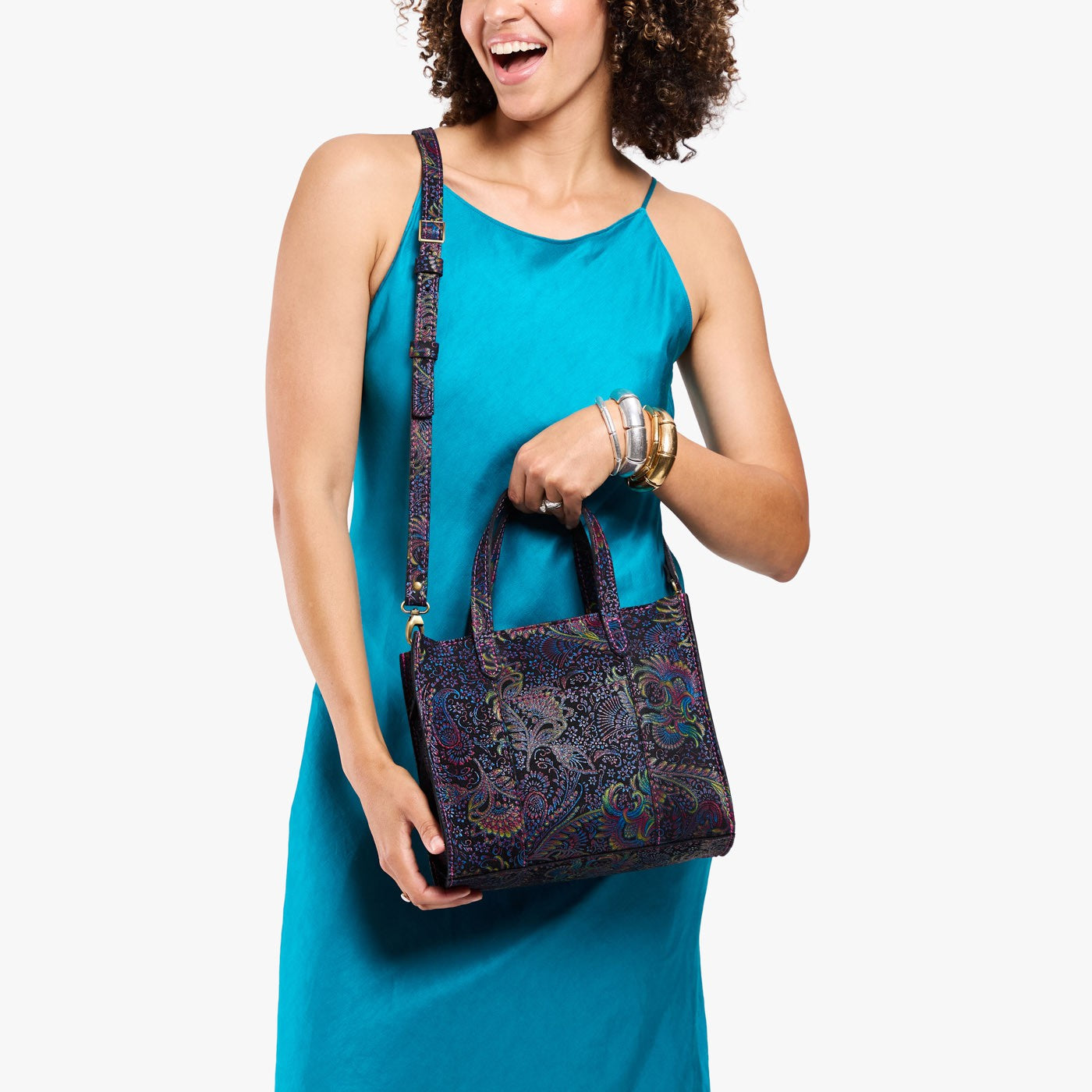 Carnival | Model holding structured mid-size tote bag with overlapping panels and crossbody strap