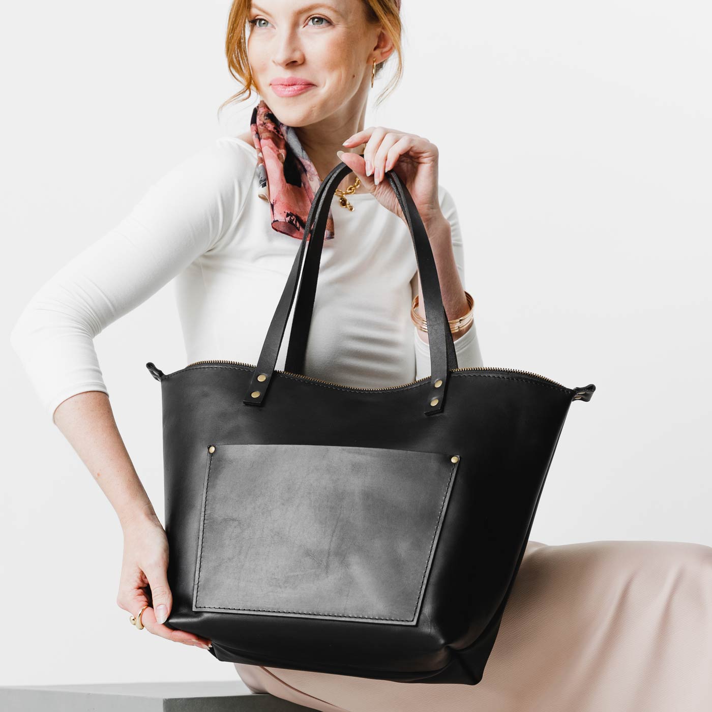Black*Zipper | Model holding large zipper leather tote bag with sturdy bridle handles and front pocket