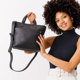 Pebbled--black Zipper | Model holding crossbody tote bag with zipper closure and front pocket