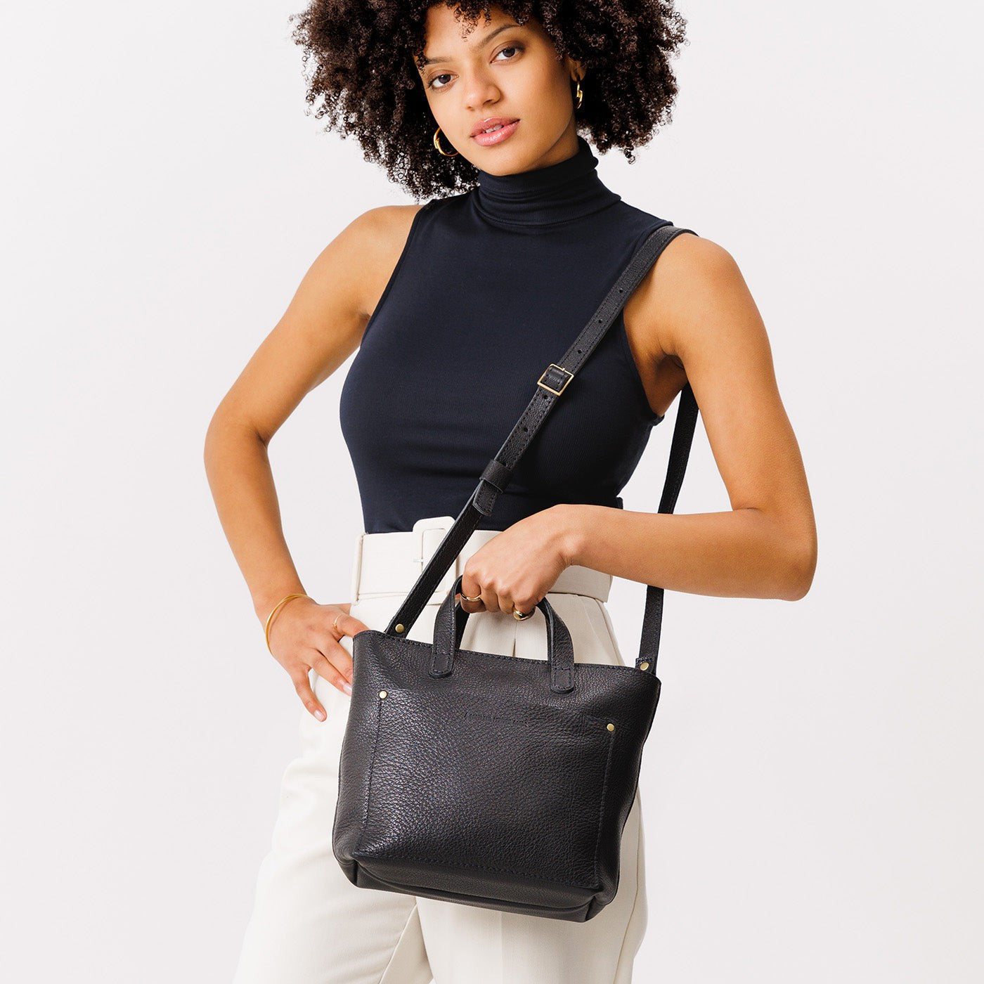 Pebbled--black*Zipper | Model holding crossbody tote bag with zipper closure and front pocket