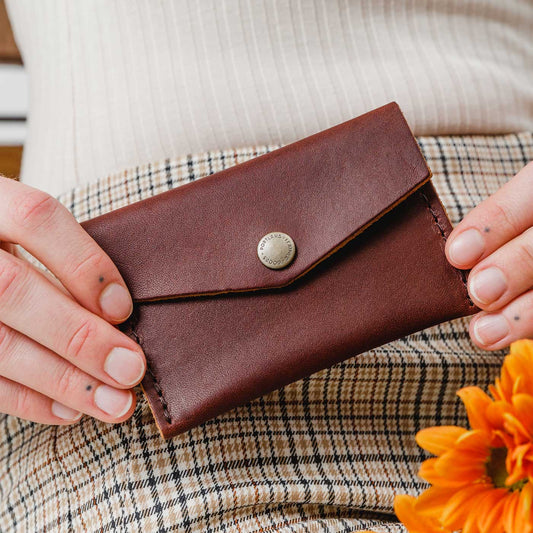 Cognac | Model holding small leather envelope wallet with snap closure
